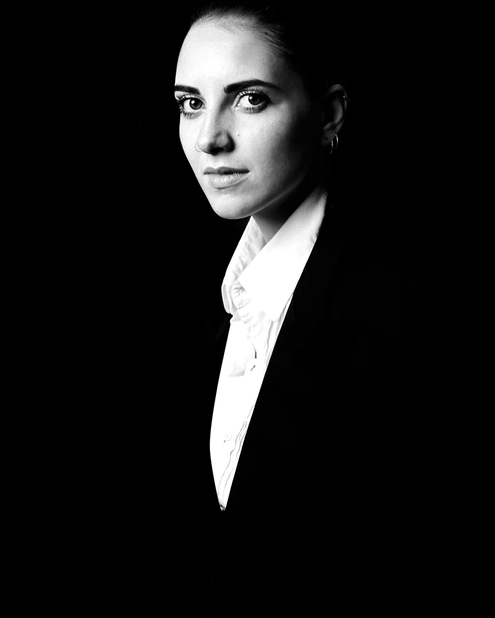 Portrait d'Élise Ashcombe, en veste noire, sur fond sombre