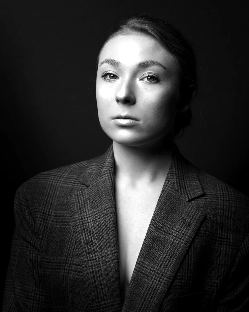 Portrait de Léa Morand, en veste à carreaux, sur fond sombre