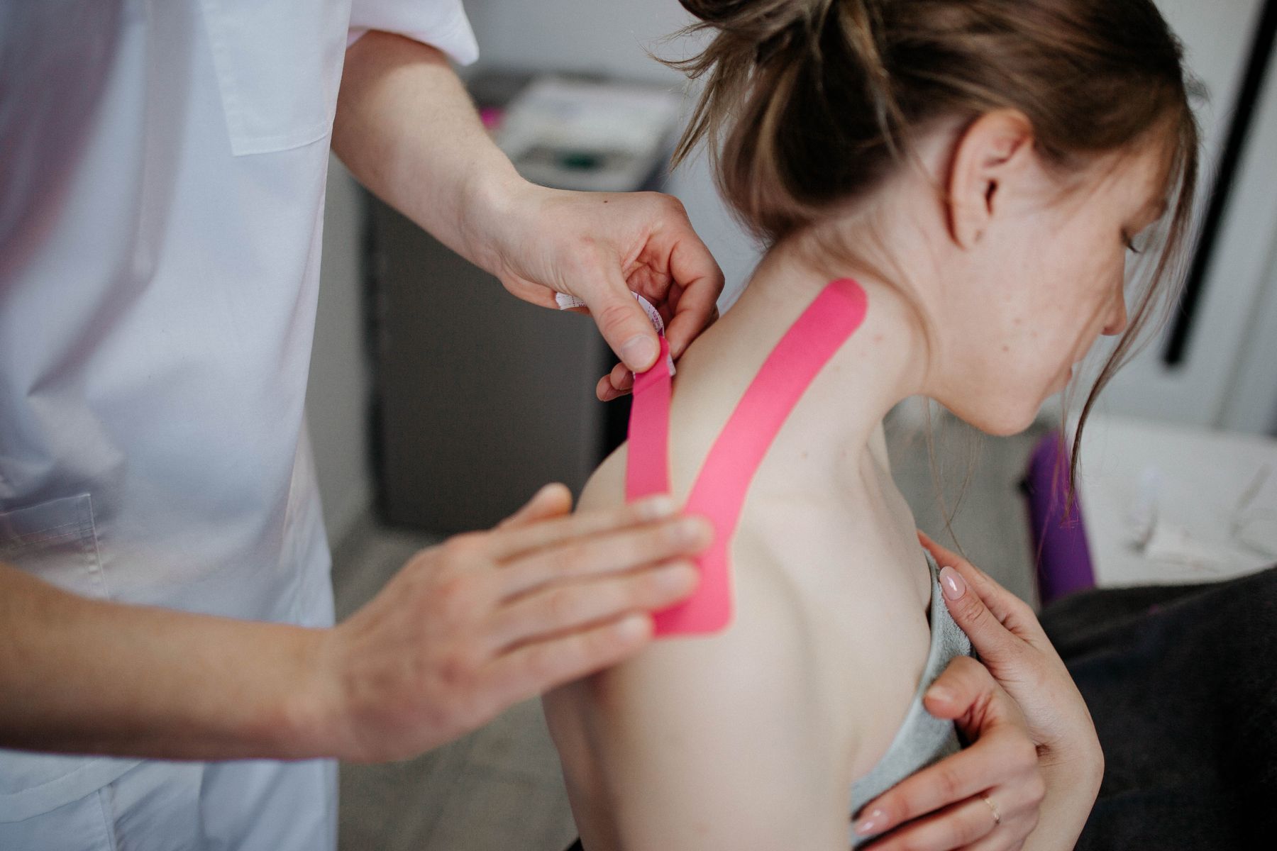 Pose d'un bandage de taping sur l'épaule d'une sportive