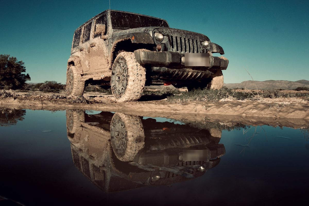 4×4 baroudeur couvert de boue au bord d'une flaque