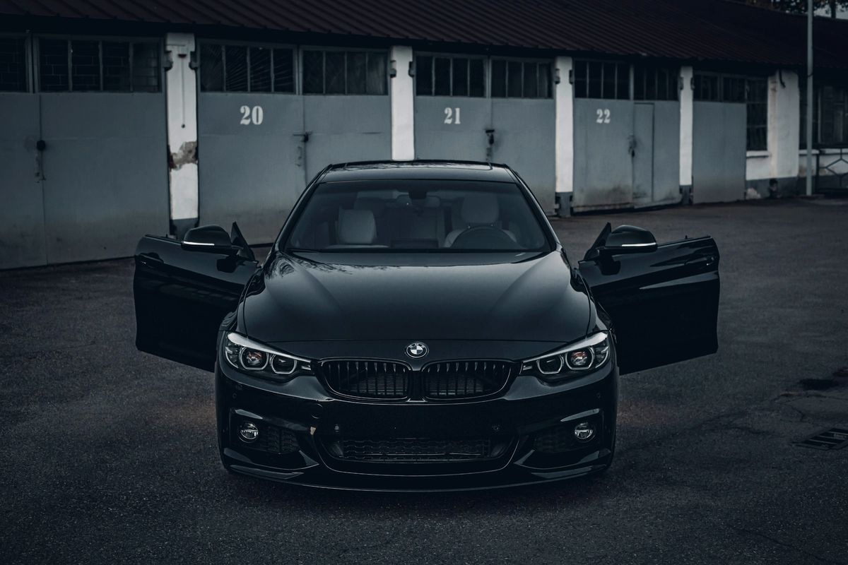 Berline noire de face, portes ouvertes, dans un garage