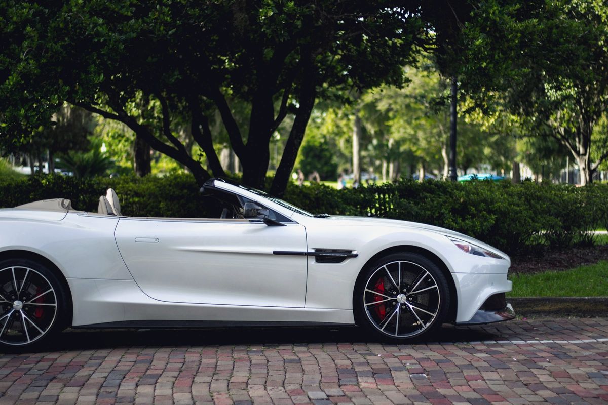 Cabriolet blanc capote ouverte, garé sous les arbres