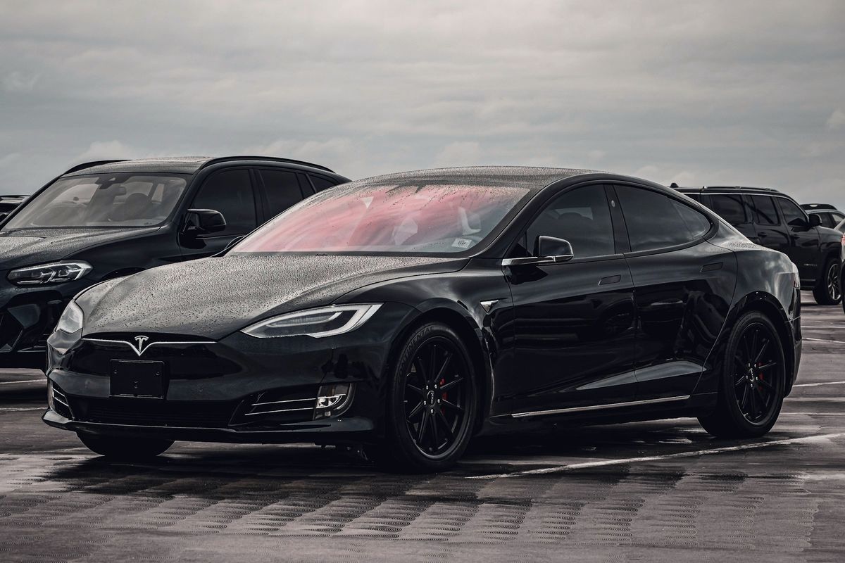 Berline électrique noire sur un parking humide