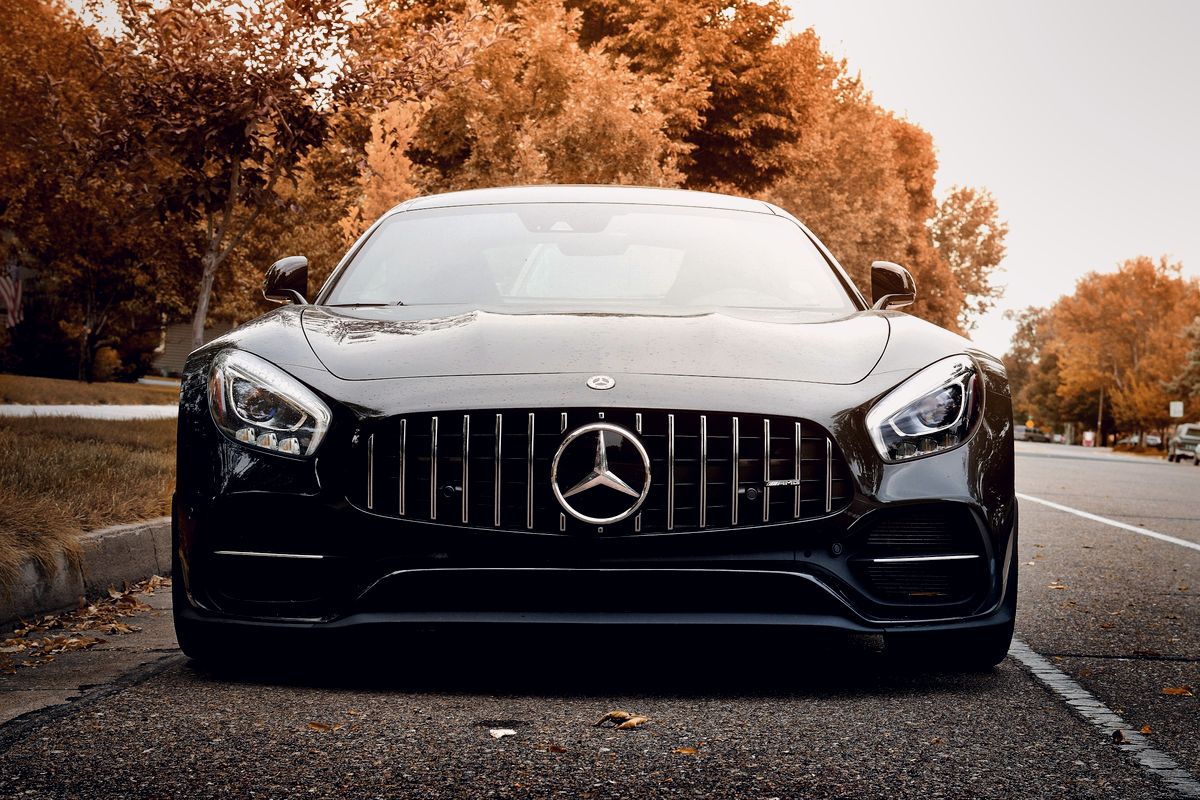 Coupé GT noir de face sur une route bordée d'arbres en automne